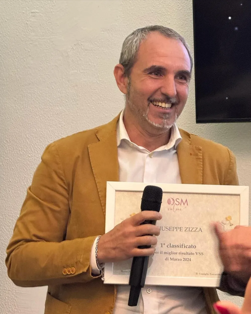 Giuseppe Zizza sorride durante un evento OSM, con il microfono in mano